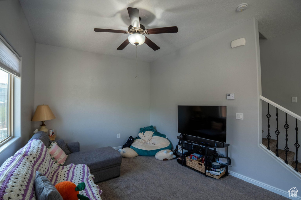 Living room featuring stairway, carpet flooring, baseboards, and a ceiling fan