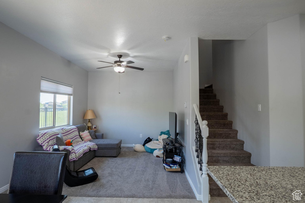Unfurnished living room with carpet flooring, stairway, baseboards, and ceiling fan