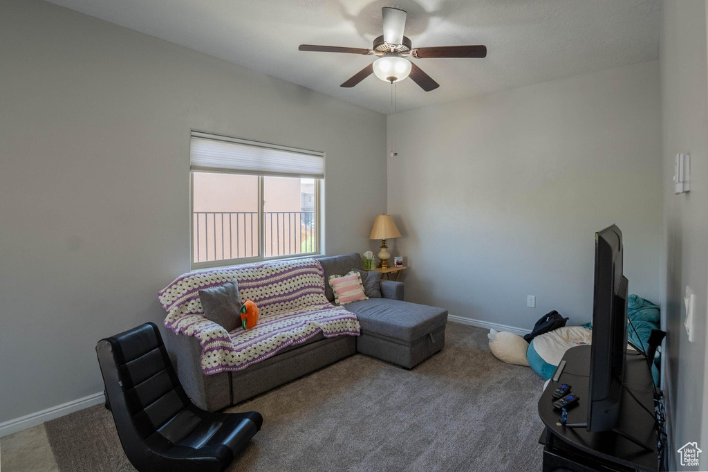 Carpeted living room featuring baseboards and ceiling fan