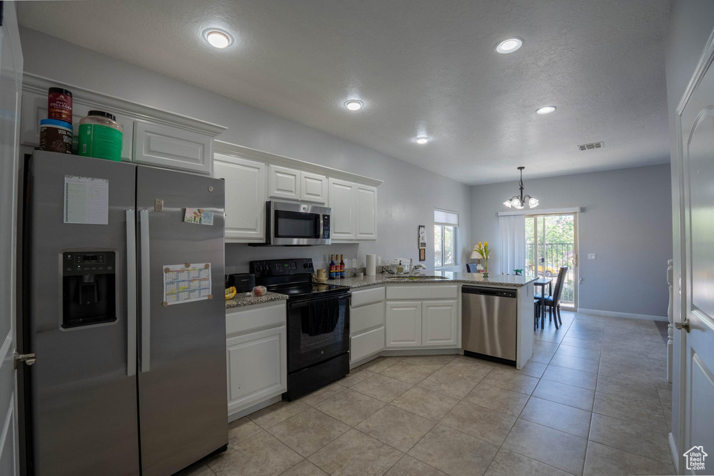 Kitchen featuring a peninsula, recessed lighting, an inviting chandelier, white cabinetry, and appliances with stainless steel finishes