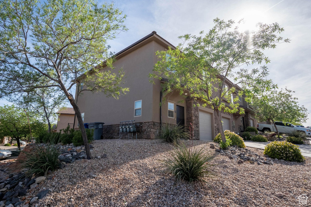 View of side of home with stone siding, stucco siding, driveway, and an attached garage