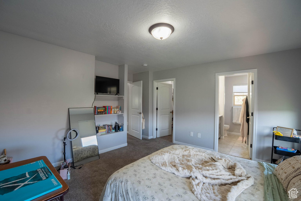 Carpeted bedroom with ensuite bath, a textured ceiling, and baseboards