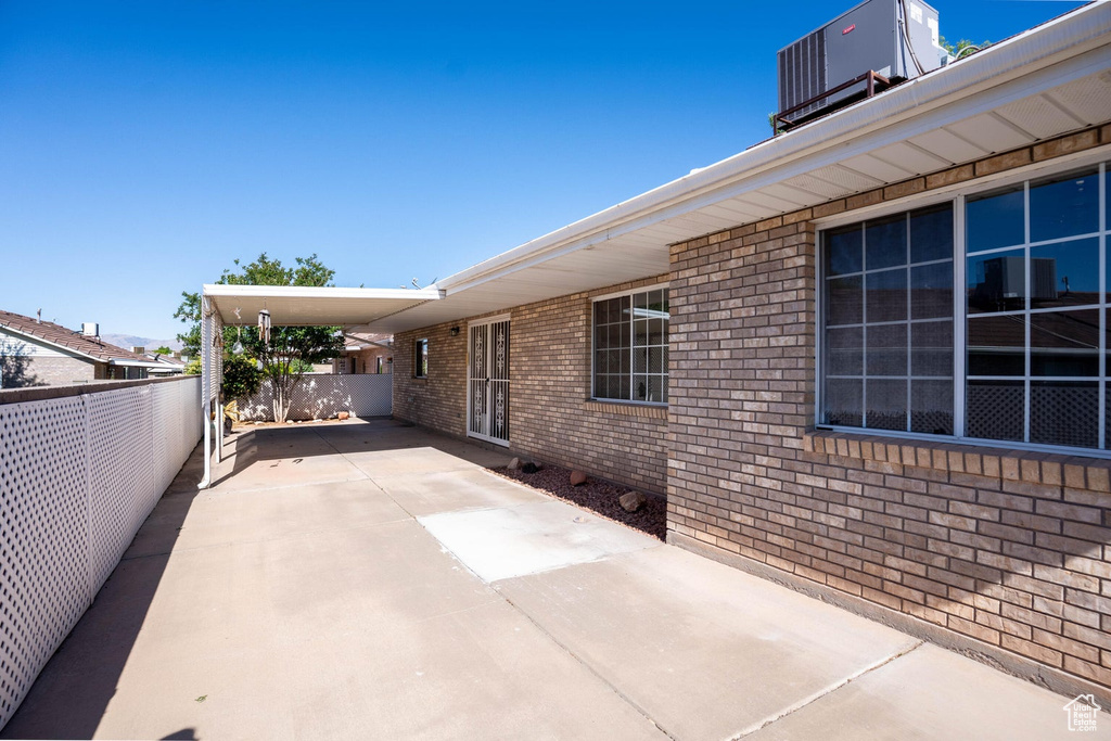 View of patio / terrace with driveway, fence, and a carport