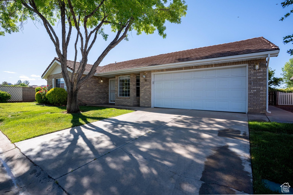View of front of property with fence, brick siding, concrete driveway, a garage, and a front lawn