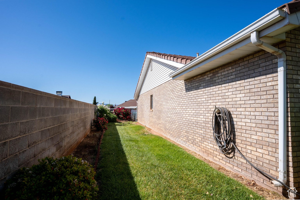 View of home's exterior with fence, brick siding, and a lawn