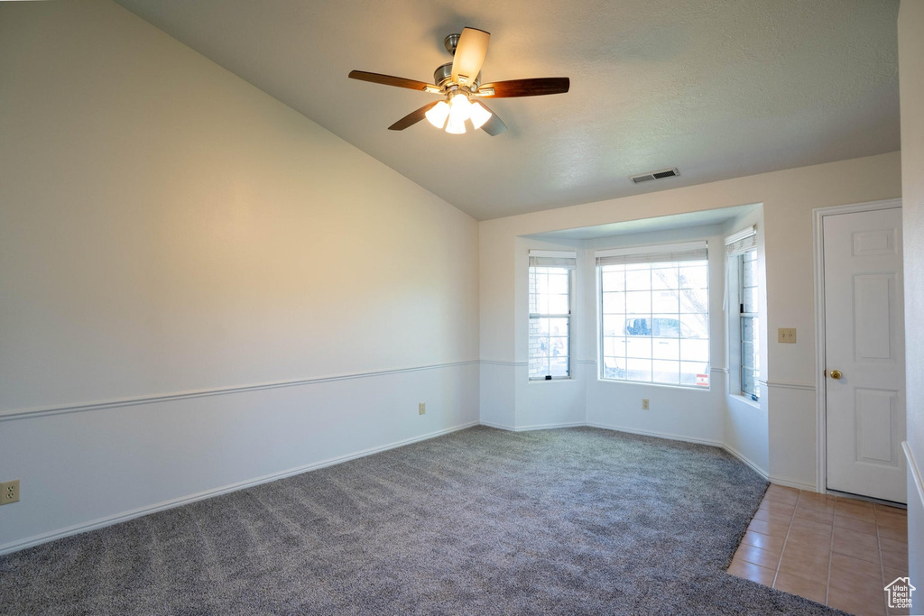 Empty room featuring ceiling fan, lofted ceiling, baseboards, and visible vents