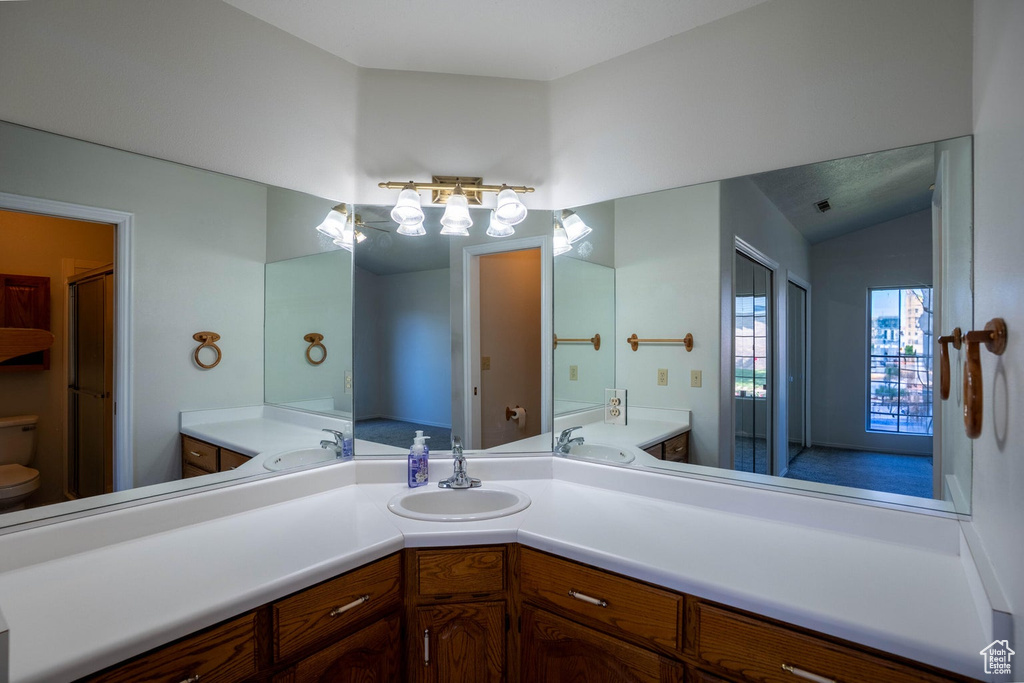 Full bathroom with lofted ceiling, vanity, and toilet