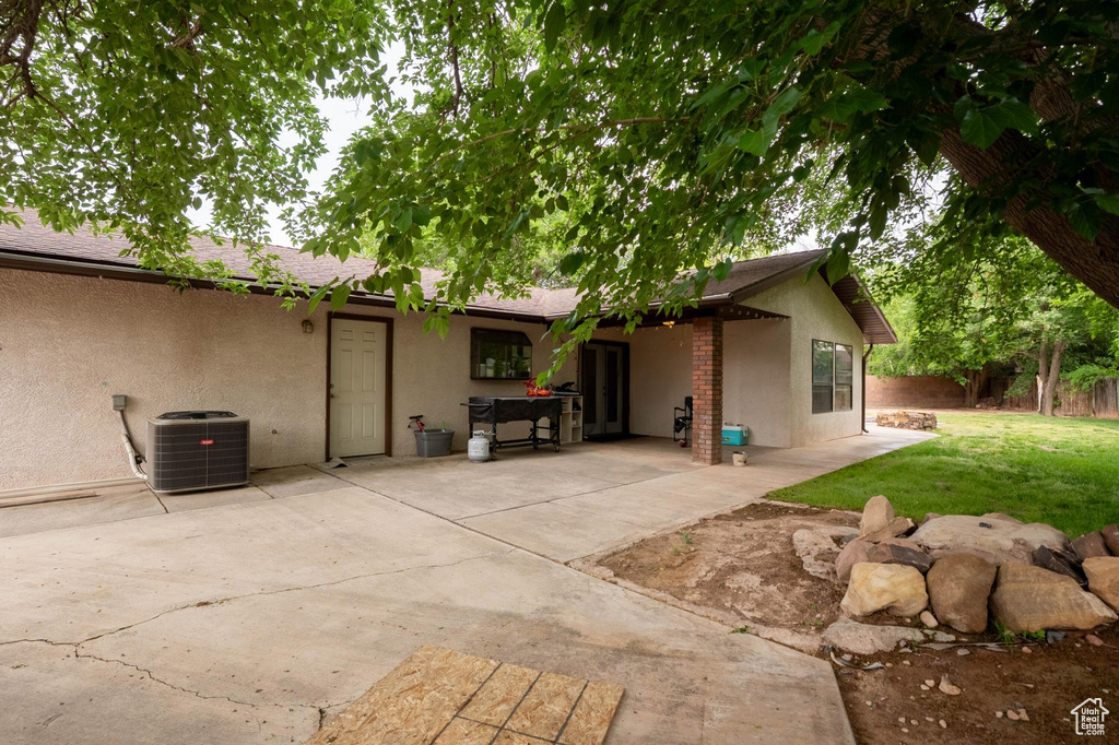 Rear view of property with a patio, stucco siding, fence, a lawn, and central AC unit