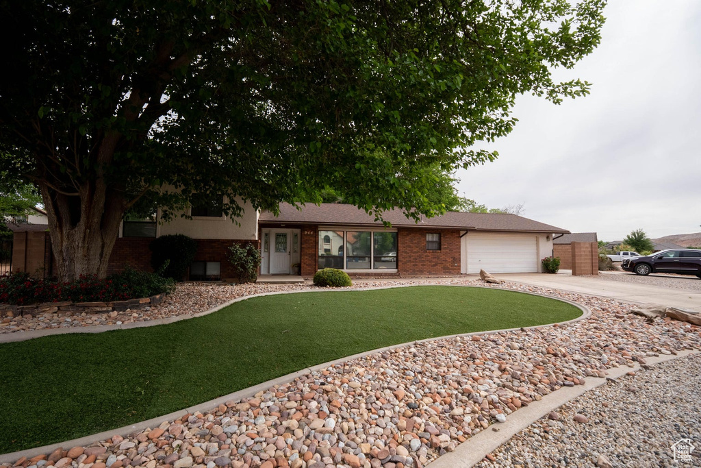 View of front facade with concrete driveway, brick siding, a front yard, and a garage