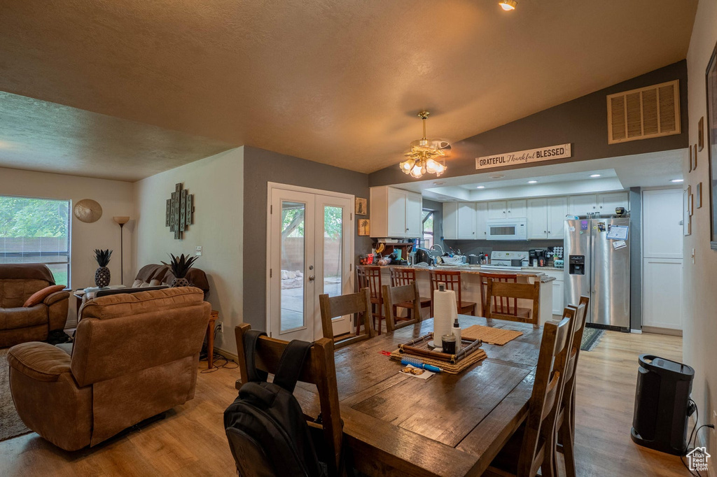 Dining area featuring light wood-type flooring, ceiling fan, lofted ceiling, and visible vents