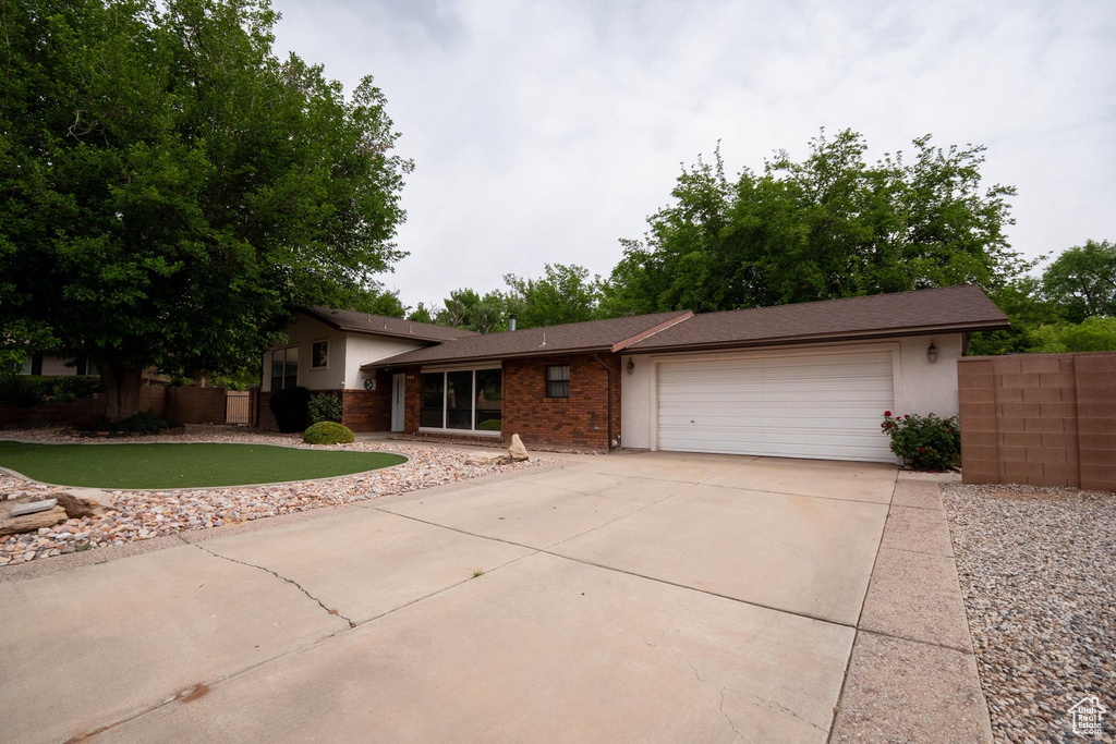 Tri-level home with fence, a garage, concrete driveway, and brick siding