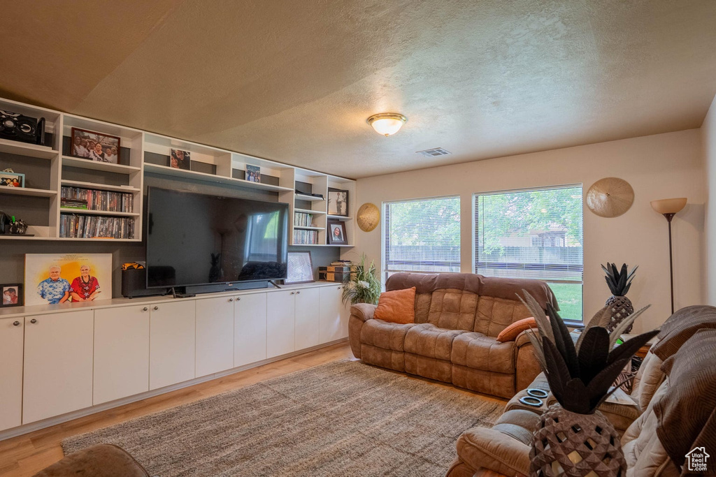Living room featuring light wood finished floors, visible vents, and a textured ceiling