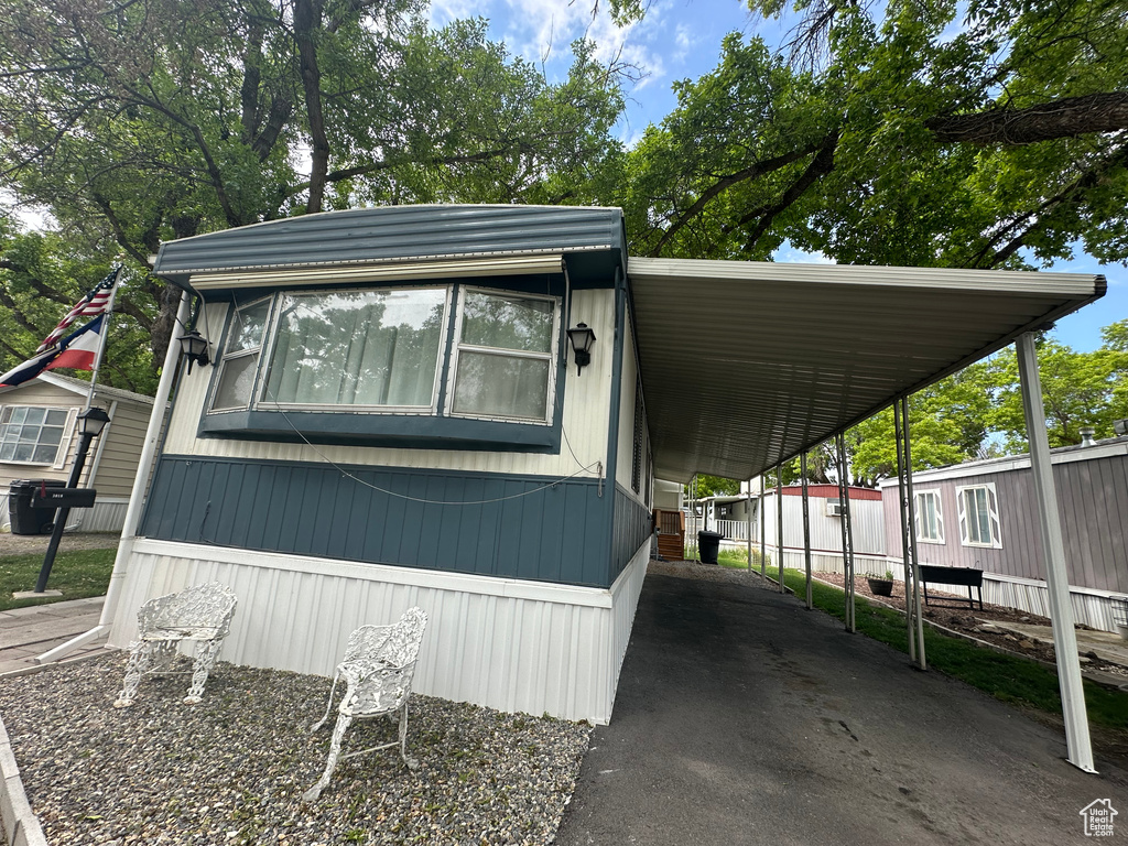 View of side of home with driveway, fence, and a carport