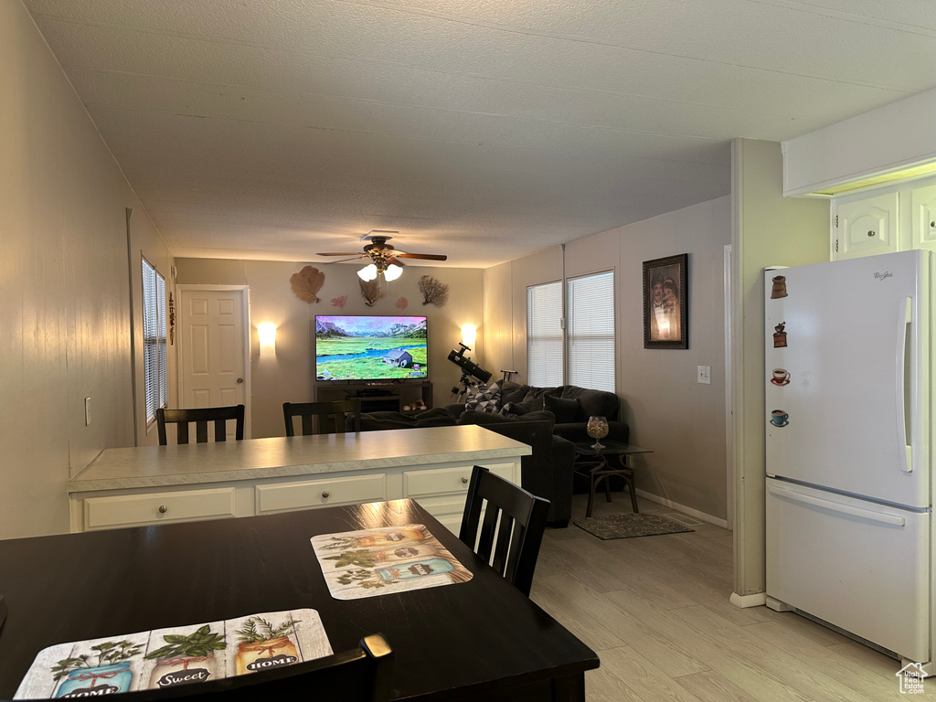 Interior space with freestanding refrigerator, ceiling fan, light wood finished floors, open floor plan, and white cabinets