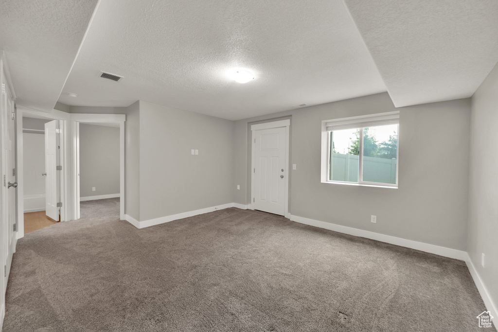 Spare room featuring carpet, visible vents, and a textured ceiling