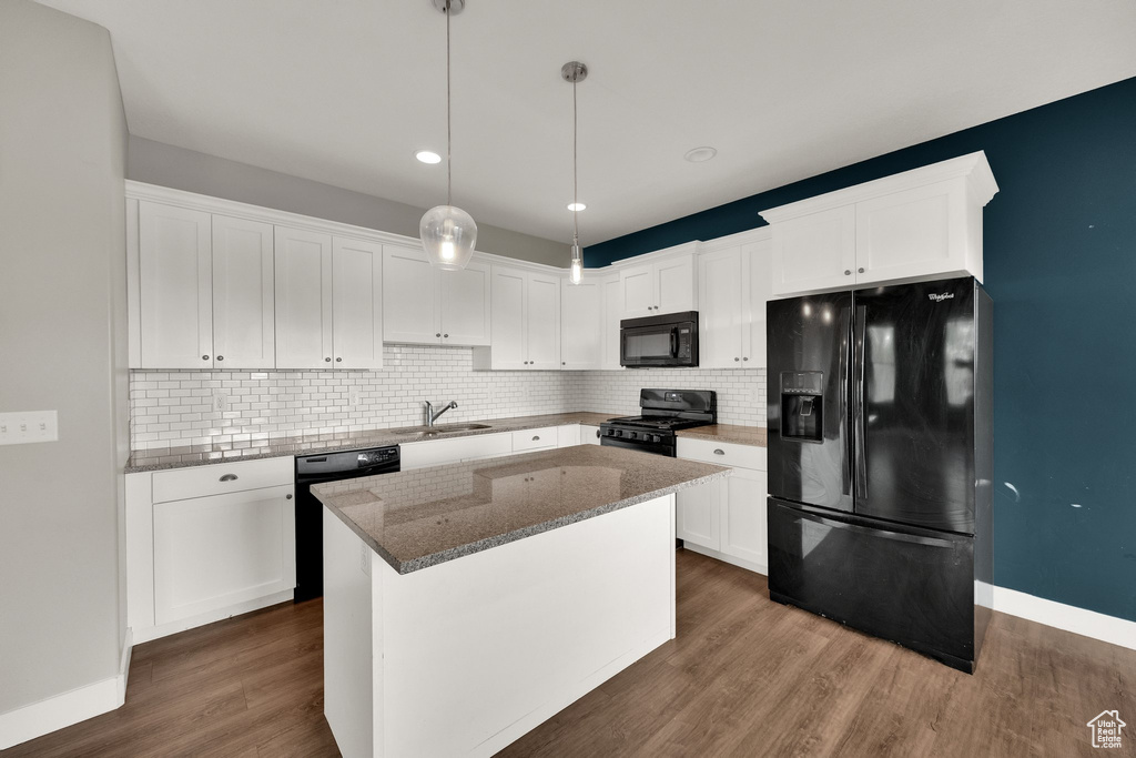 Kitchen with stone counters, a sink, white cabinetry, black appliances, and tasteful backsplash