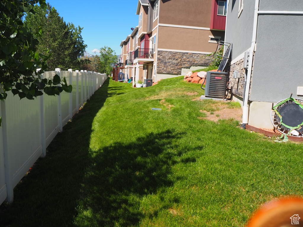 View of yard with cooling unit and fence