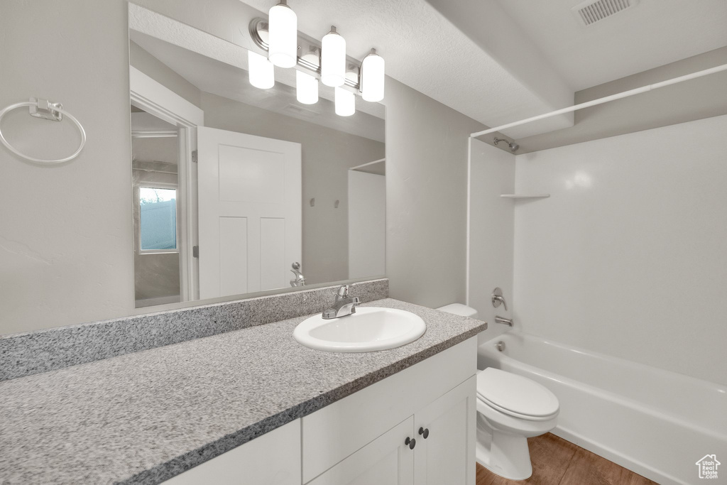 Full bathroom with toilet, wood finished floors, shower / washtub combination, visible vents, and vanity