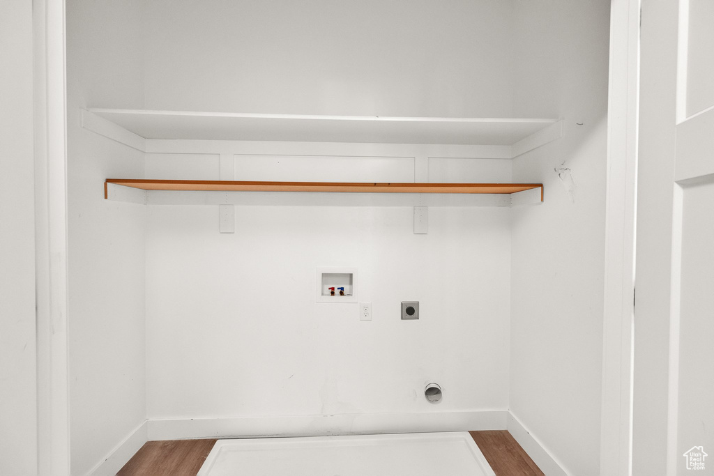 Clothes washing area with laundry area, electric dryer hookup, hookup for a washing machine, and dark wood finished floors