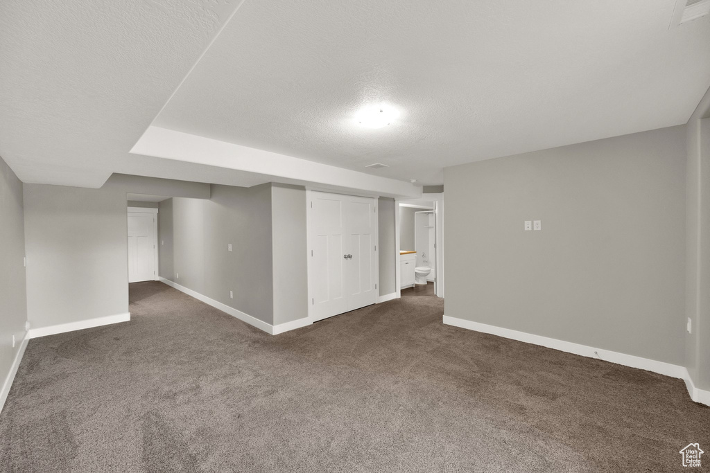 Finished basement with baseboards, dark carpet, and a textured ceiling