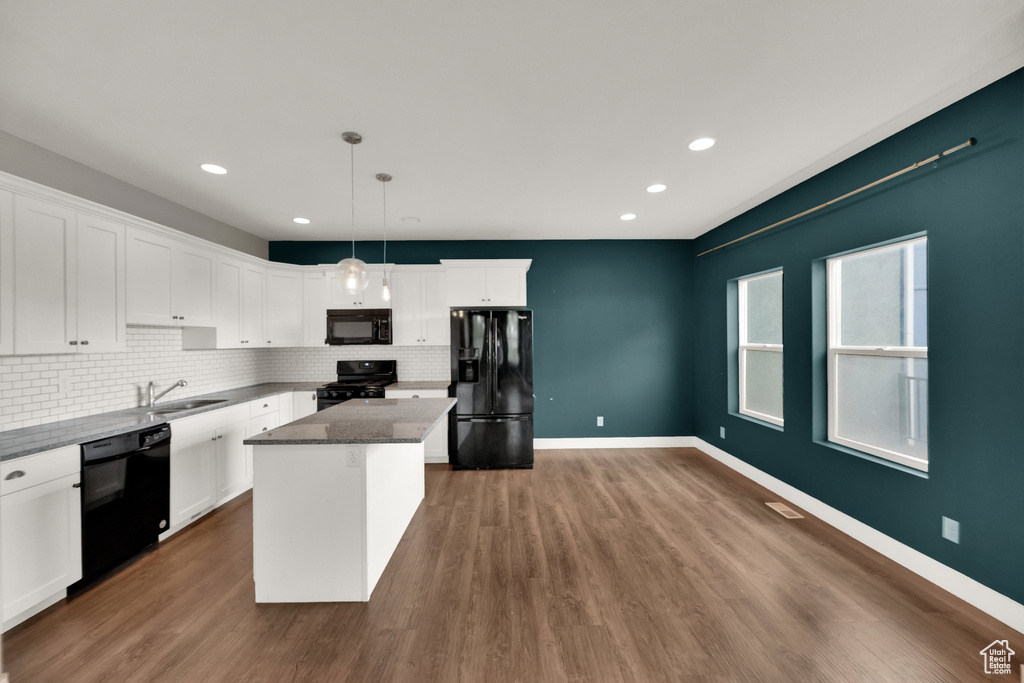 Kitchen with tasteful backsplash, black appliances, dark wood-style flooring, white cabinetry, and a kitchen island