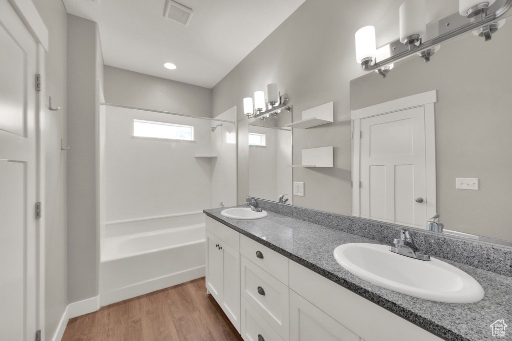 Full bathroom featuring visible vents, wood finished floors, tub / shower combination, and a sink