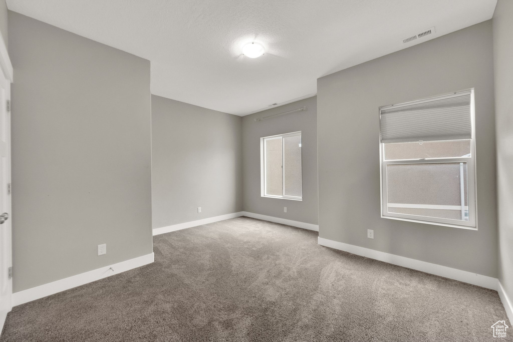 Carpeted empty room with visible vents and baseboards