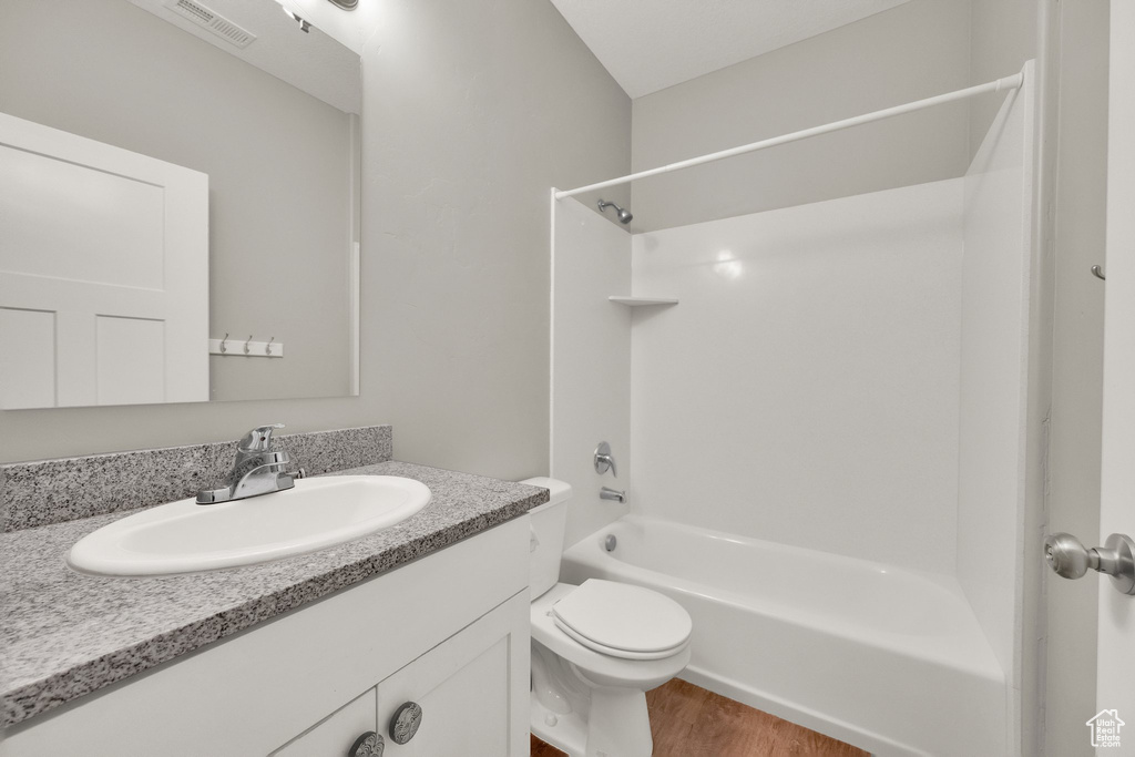 Full bath featuring toilet, wood finished floors, vanity, visible vents, and tub / shower combination