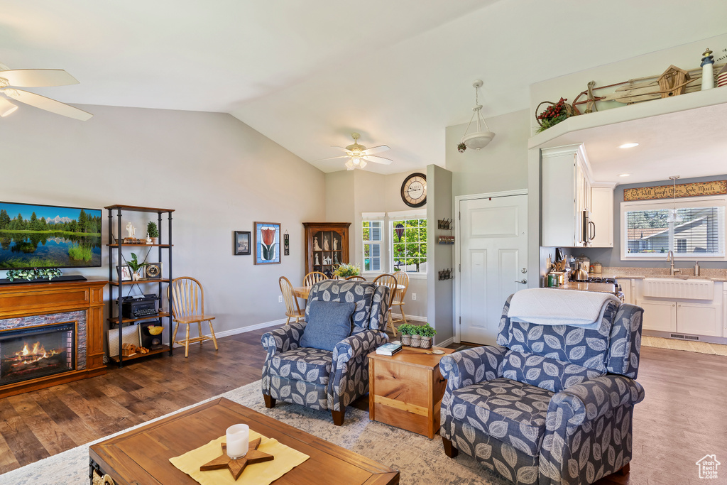 Living room featuring wood finished floors, baseboards, ceiling fan, and high vaulted ceiling