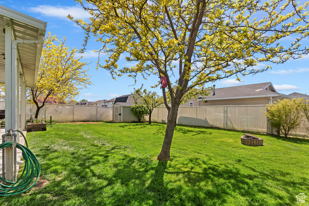 View of yard featuring a fenced backyard, an outdoor fire pit, a storage shed, and an outbuilding