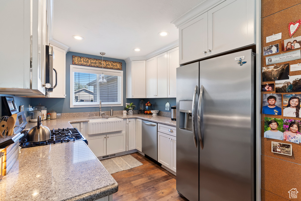Kitchen featuring a sink, stainless steel appliances, white cabinetry, dark wood-type flooring, and recessed lighting