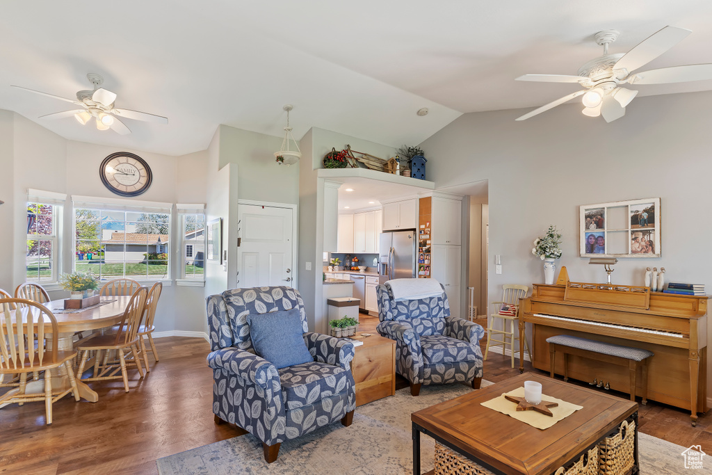 Living room with wood finished floors, baseboards, ceiling fan, and high vaulted ceiling