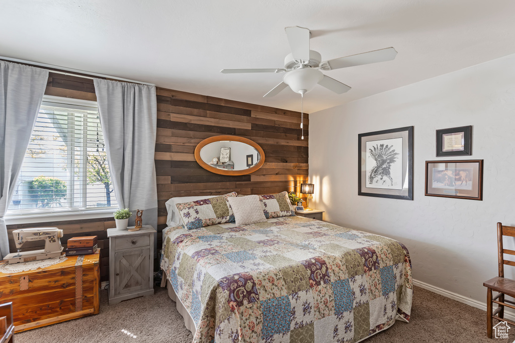 Bedroom featuring carpet flooring, wood walls, baseboards, and ceiling fan