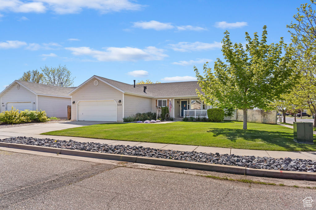 Ranch-style house with a front yard, a shingled roof, an attached garage, and driveway