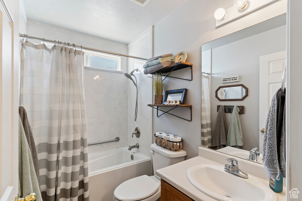 Full bathroom featuring toilet, vanity, and shower / bath combo with shower curtain