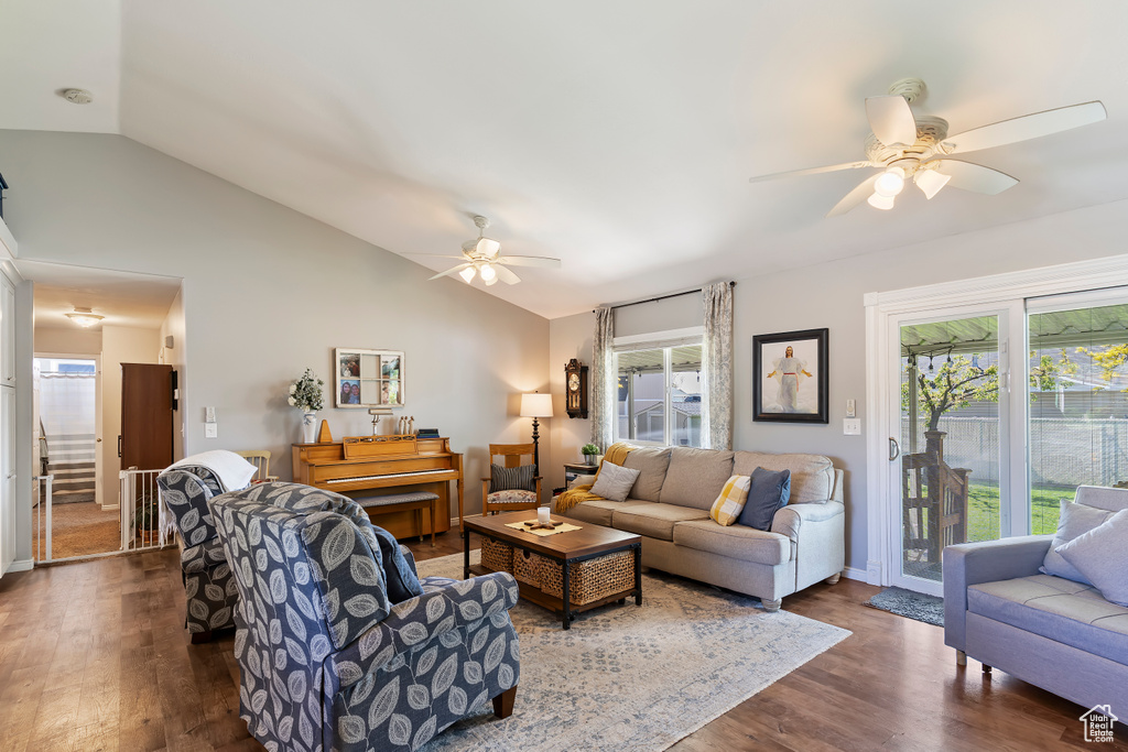 Living room with lofted ceiling, baseboards, a ceiling fan, and dark wood-type flooring