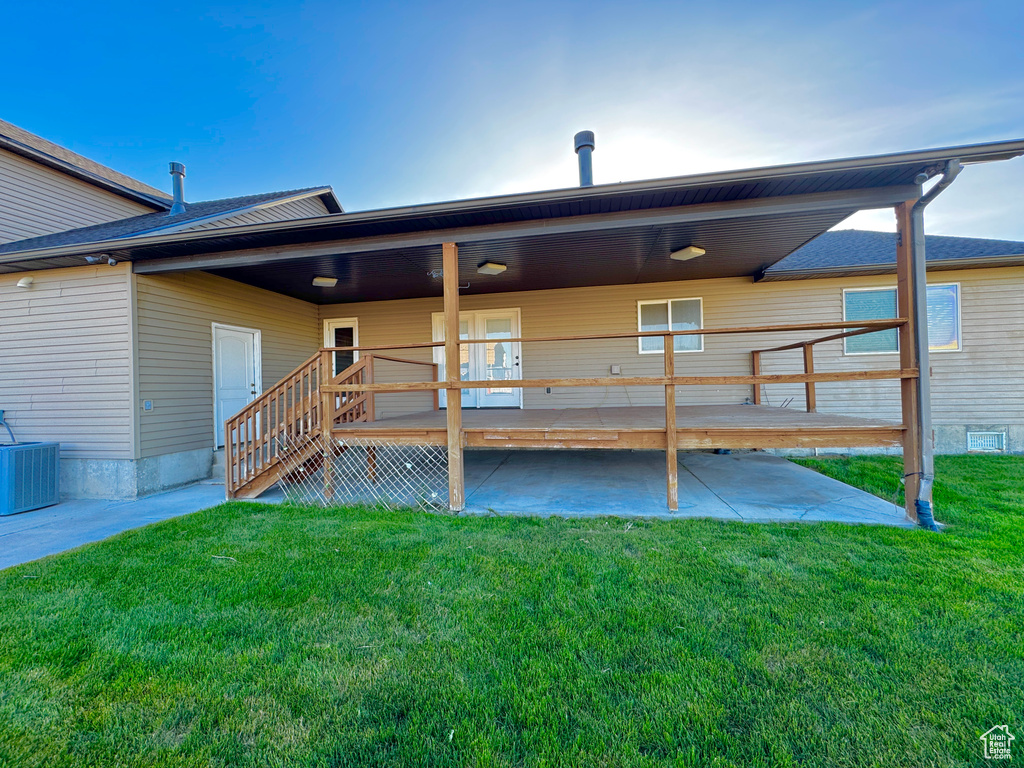 Rear view of property featuring cooling unit, a patio, and a yard