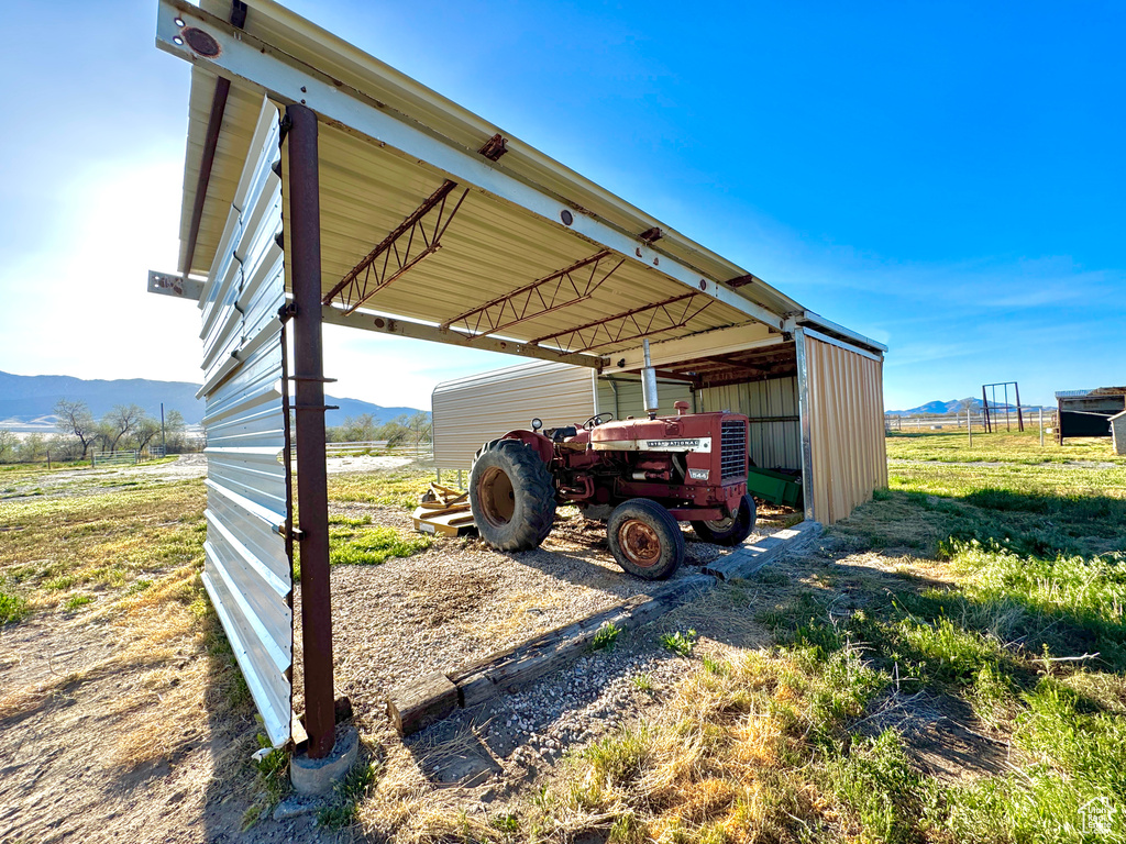 View of parking featuring a mountain view, a pole building, dirt driveway, and a carport
