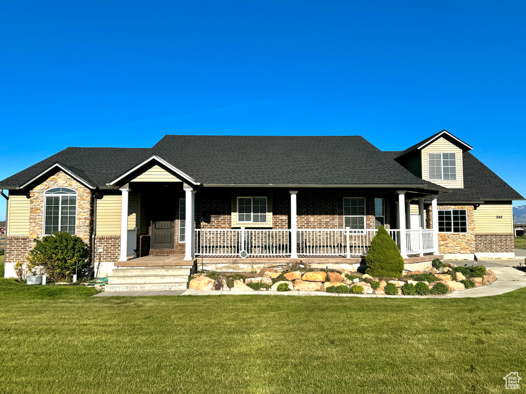 Single story home featuring a porch, brick siding, and a front lawn