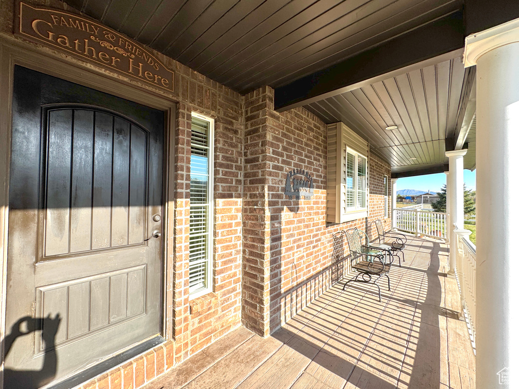View of exterior entry with brick siding and covered porch
