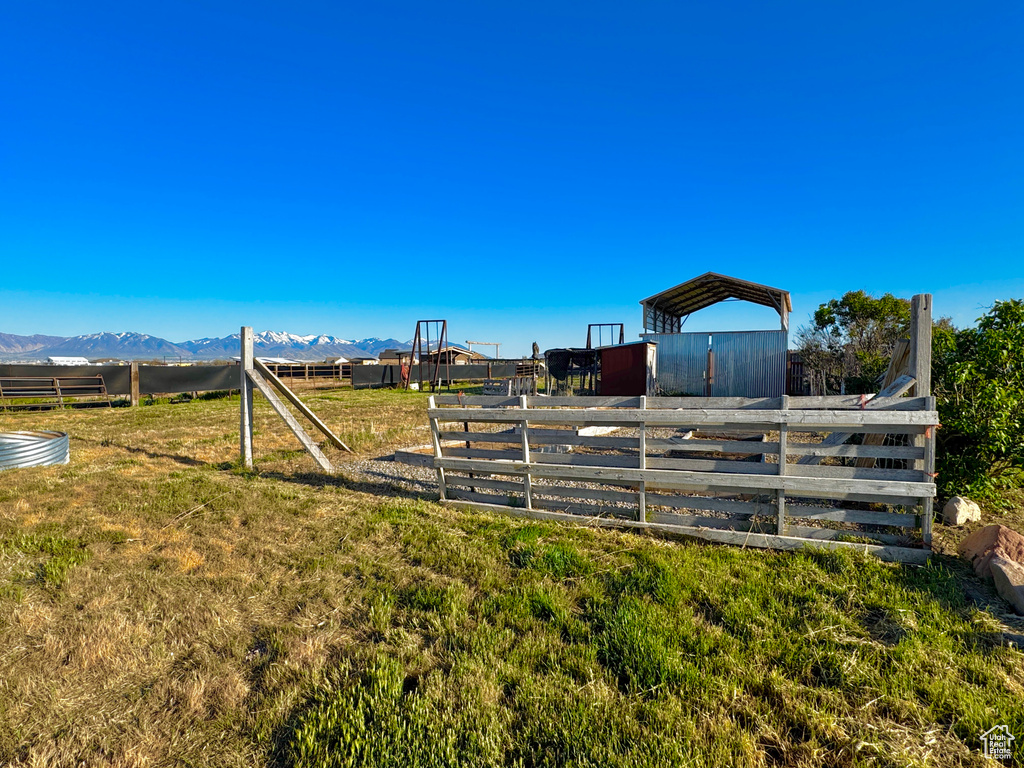 View of yard featuring a mountain view, an exterior structure, fence, an outdoor structure, and a detached carport
