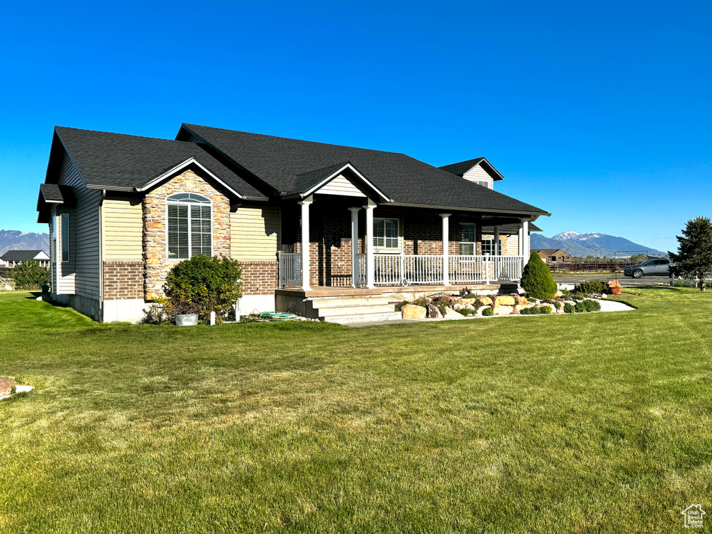 Ranch-style home featuring a porch, brick siding, a front lawn, and a mountain view