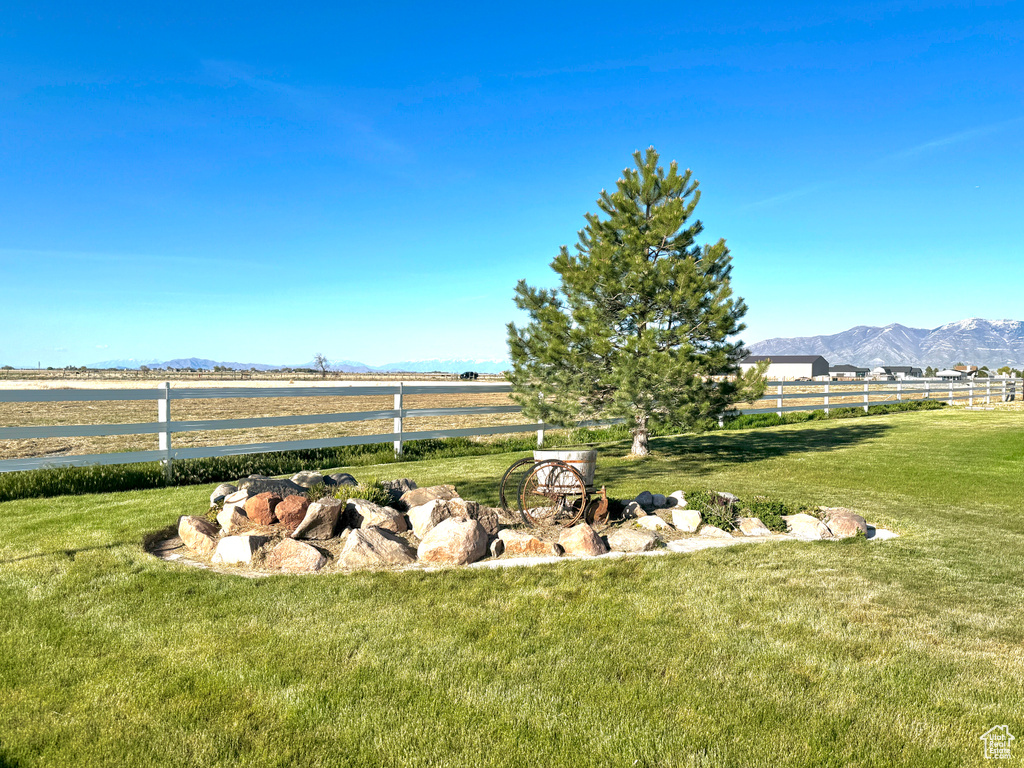 View of yard featuring a rural view, a mountain view, and fence