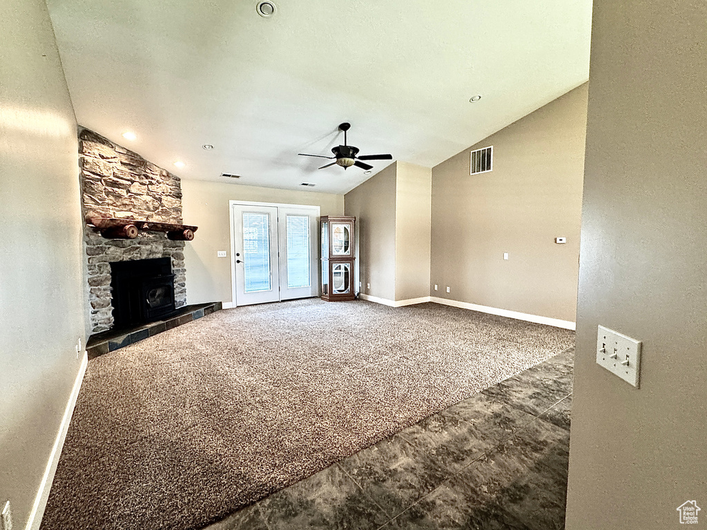 Unfurnished living room featuring a ceiling fan, baseboards, visible vents, vaulted ceiling, and a fireplace
