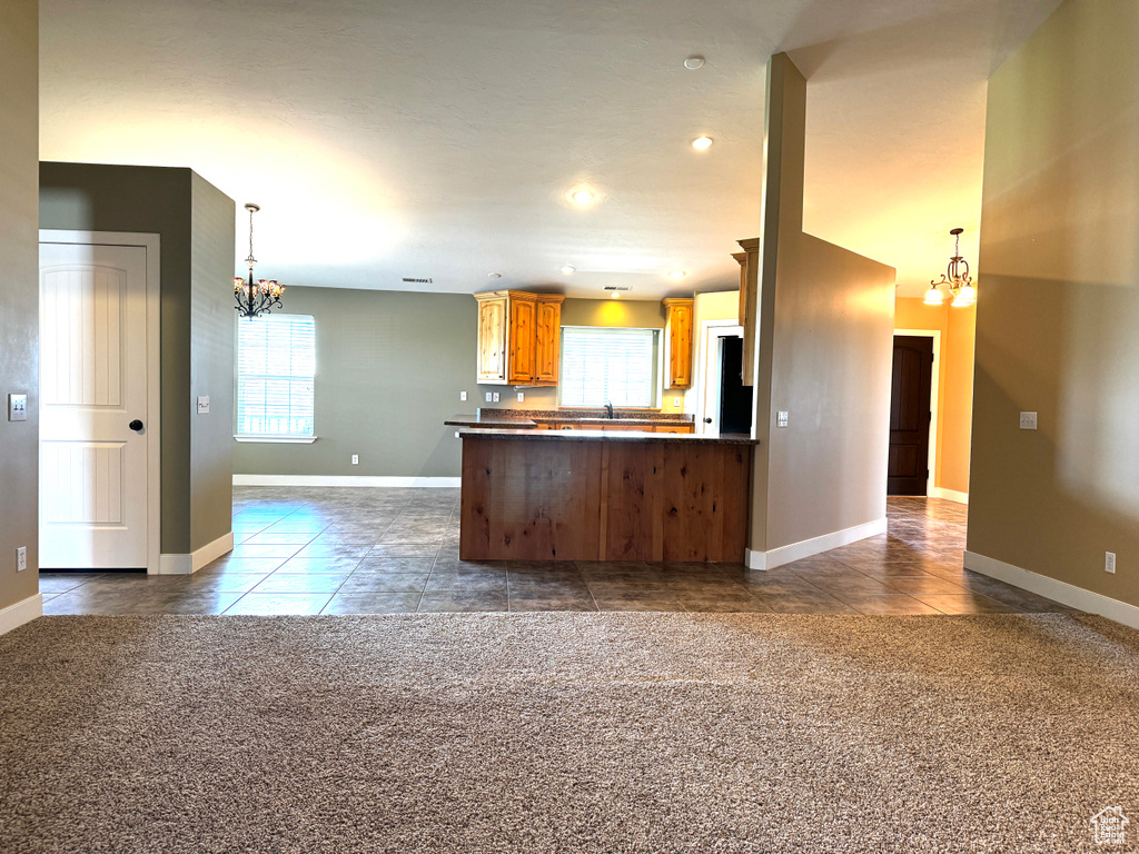 Kitchen with an inviting chandelier, dark tile patterned floors, open floor plan, and dark countertops