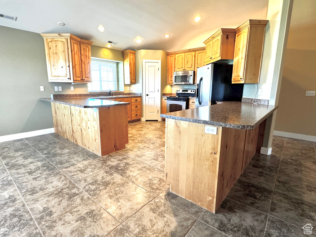 Kitchen featuring baseboards, visible vents, a peninsula, dark countertops, and stainless steel appliances