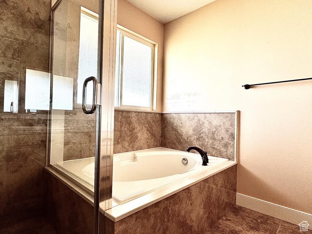Full bathroom with baseboards, tile patterned floors, a garden tub, and a shower with door
