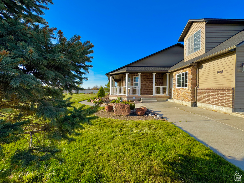 Exterior space with a porch, brick siding, and a front yard