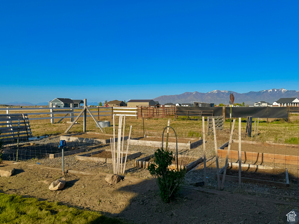 View of yard with a rural view, a vegetable garden, a mountain view, and fence