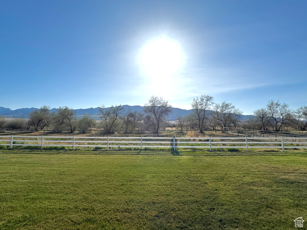 View of yard with fence, a rural view, and a mountain view